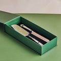 A 2-piece cake knife and server set with mother of pearl handles, placed in a green box on a green background.